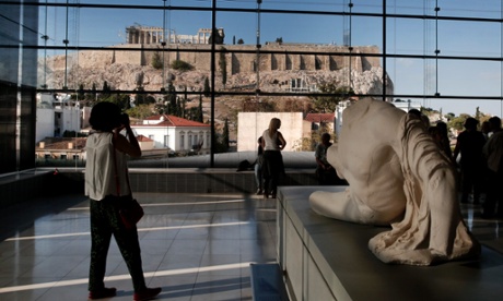 Visitors to Athens' Acropolis Museum look at the view to the ancient Temple of Parthenon.