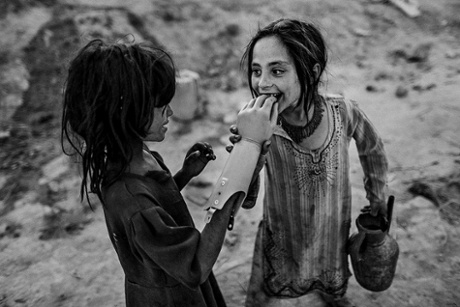 Two Afghan girls play with an artificial hand, south of Kabul