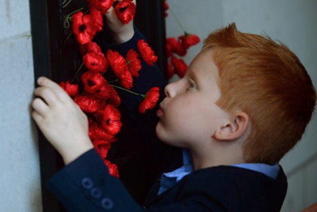 Five-year-old Alex Hopkins places a poppy next to his father's name at the Australian War Memorial in Canberra.