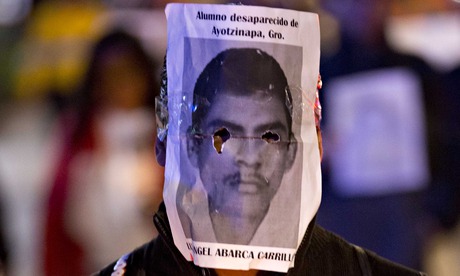 A demonstrator wears a photograph of one of the missing students at a protest in Mexico City