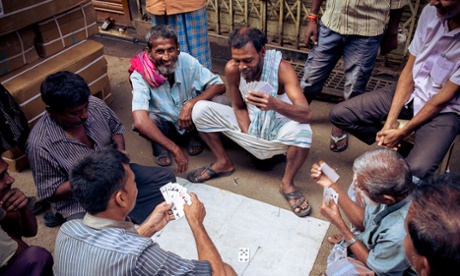 Men play a game of cards amid the bustle of the city. Kolkata, India