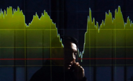 A pedestrian holding his mobile phone is reflected on an electronic board showing the graph of the recent fluctuations of Japan's Nikkei average outside a brokerage in Tokyo February 5, 2014.