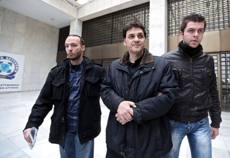 The former chief executive of the Hellenic Postbank, Angelos Filippidis (C) is escorted by plain cloth policemen outside the Athens police headquarters on February 5, 2014.