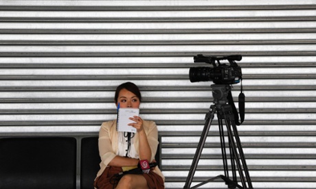 A reporter from China waits by her camera at the Kuala Lumpur International Airport as search planes continue to look for the missing Malaysia Airlines aircraft, Flight MH370.