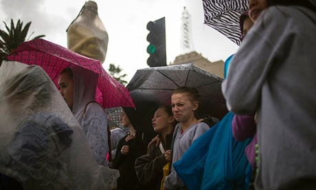 Fans wait by the red carpet as the rain comes down on the 86th Oscars