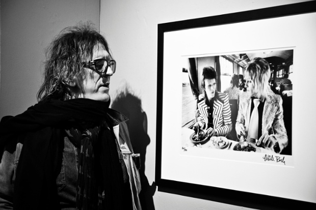 Mick Rock looking at his photograph of David Bowie and Mick Ronson from 1973