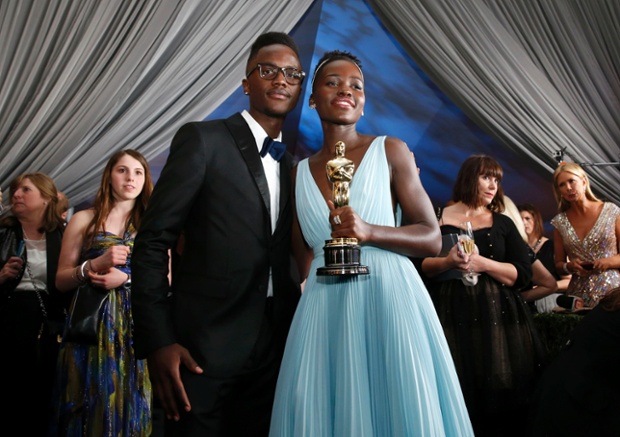 Lupita Nyong'o holds her Oscar for Best Supporting Actress while posing with her brother Julian Nyong'o at the Governors Ball