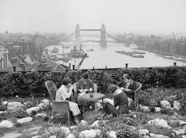 Four women have lunch in the roof garden on Adelaide House, overlooking the River Thames and Tower Bridge, circa 1934.