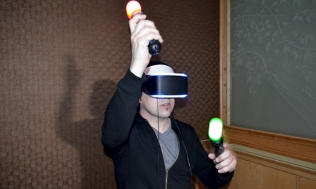 A VR headset-wearer moves his hands around, holding the controllers which have coloured lights on them