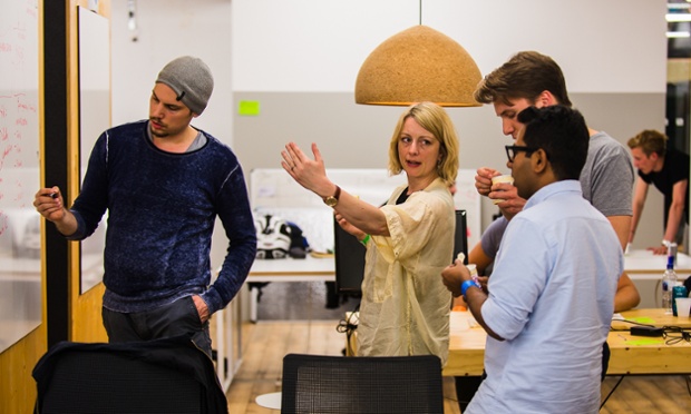 Four participants gesture in front of a white board