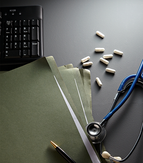 A keyboard, files, a stethoscope, a pen and loose pills