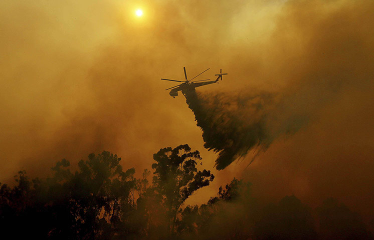 20 Photos: A helicopter drops water on a wildfire in Fallbrook, California