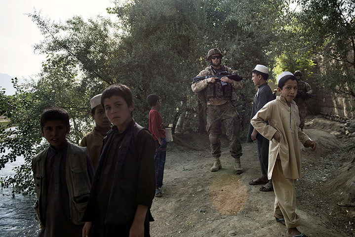 20 photos: Local Afghan children stand near a Czech soldier on patrol in Parwan