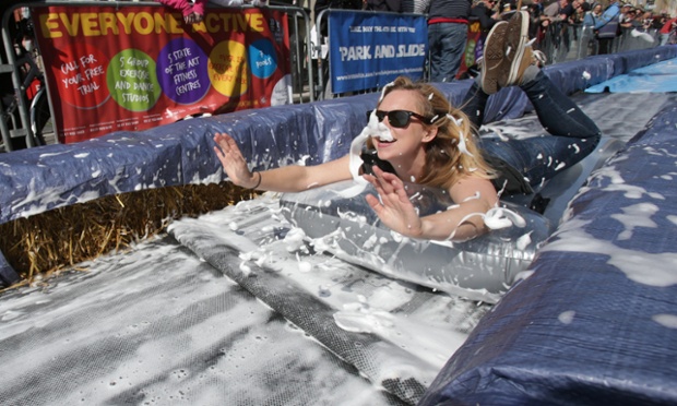 A participant on a lilo slides down a giant water slide that has been installed down Park Street