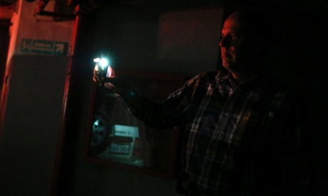 A man uses light from his phone to find his car during a blackout in Caracas.