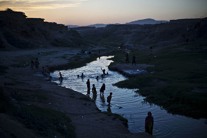 20 Photos: Internally displaced children play ina polluted stream near Islamabad