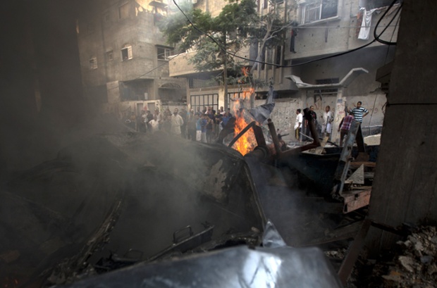 Palestinians stand looking at a destroyed building hit by an Israeli air strike in Gaza City. The Israeli air force launched raids on more than 300 targets in attacks against Hamas in the Gaza Strip overnight in response to rocket fire.