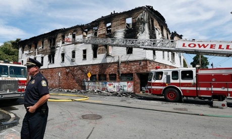 A policeman secures the scene of a burned three-story apartment and business building in Lowell.