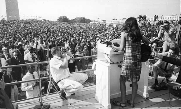 Baez performs onstage for the crowd gathered on the Mall during the Civil Rights March on Washington, D.C., August 29, 1963
