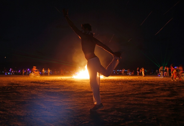 Omri Cohen dances around a burning art installation.