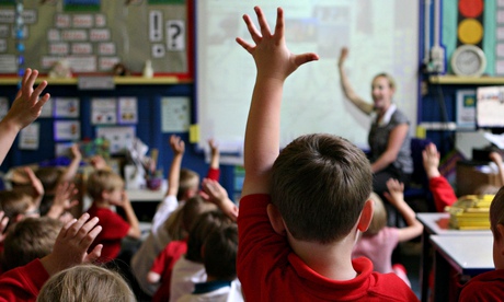 Schoolchildren raise their hands to answer a question from the teacher. 