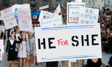 A model holds a sign reading He for She on the catwalk