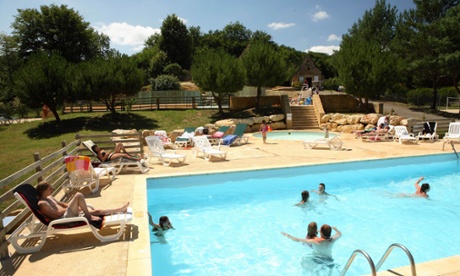 People in a swimming pool and sunbathing around it at Le Val d'Ussel Eurocamp