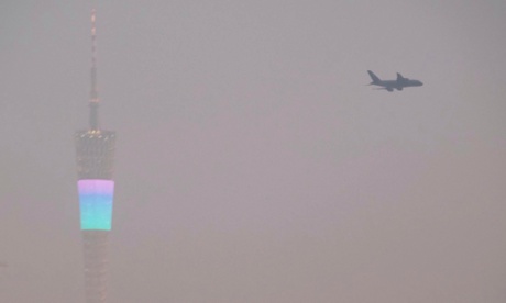 An airplane flies past the Canton Tower (L), or Guangzhou TV Tower, during a hazy day in Guangzhou, Guangdong province January 21, 2015.