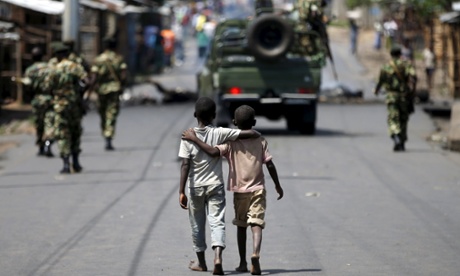 Boys walk behind patrolling soldiers in Bujumbura on Friday