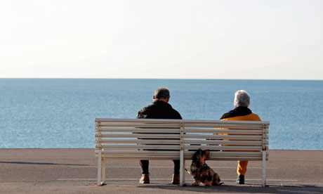 Elderly people sit on a bench by the seaside