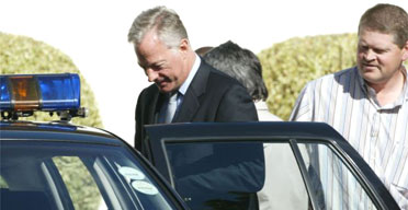 Mark Thatcher is escorted by police from his Cape Town home