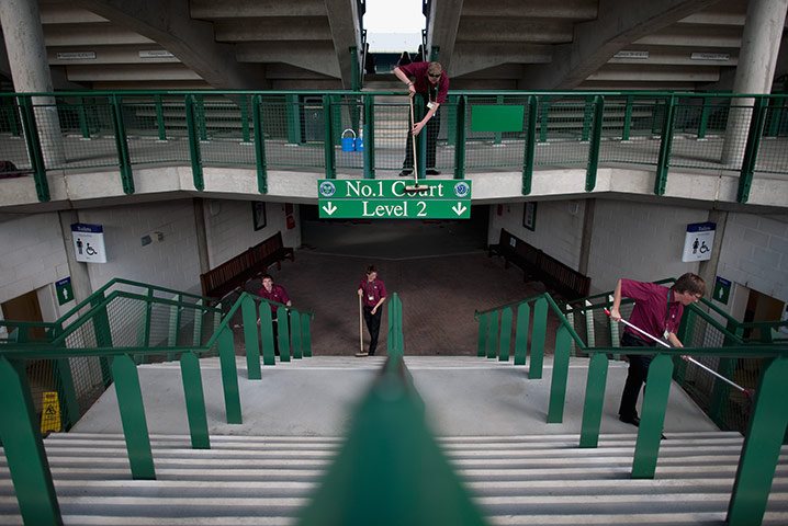 Wimbledon photo book: The workforce cleans an entrance and signs around Court 1
