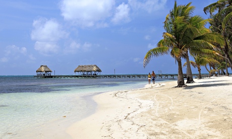 A young couple walking along the beach on the island of Ambergris Caye in Belize