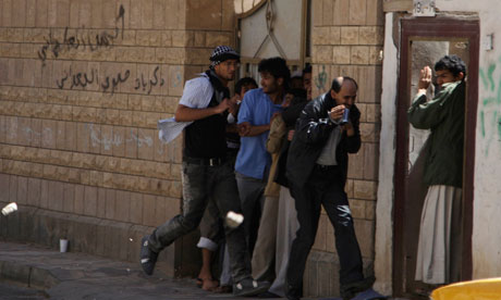 A journalist and bystanders take shelter from rocks thrown by government supporters in Sana'a, Yemen