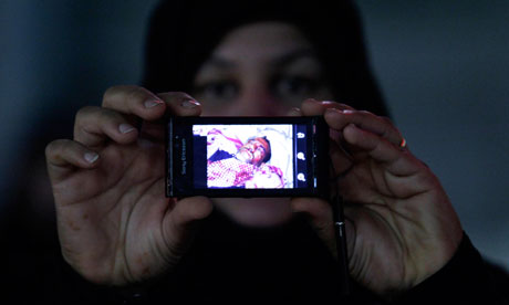A Bahraini anti-government demonstrator shows a picture of a wounded man