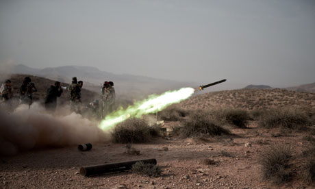 Libyan rebel fighters launch a rocket at  pro-Gaddafi forces at the front line near Gualish